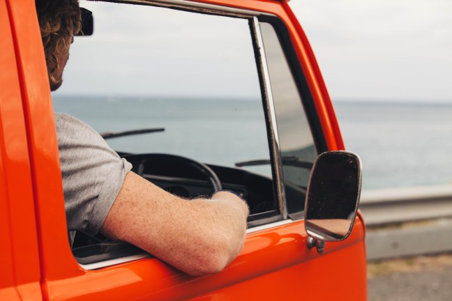 This photo shows a man leaning out of a van window