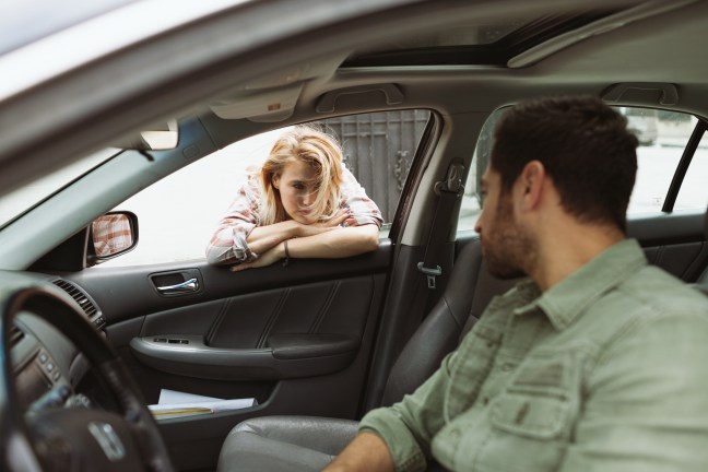This photo shows a man in the driver seat talking to a woman leaning in through the passenger window
