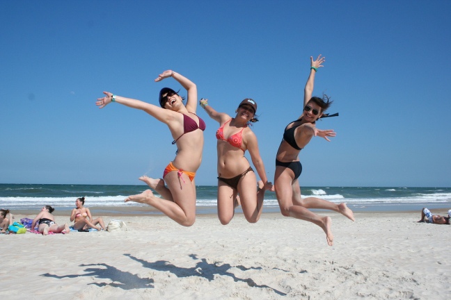 This photo shows three women jumping together on the beach