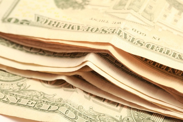 This photo shows a pile of cash with a $20 bill on top